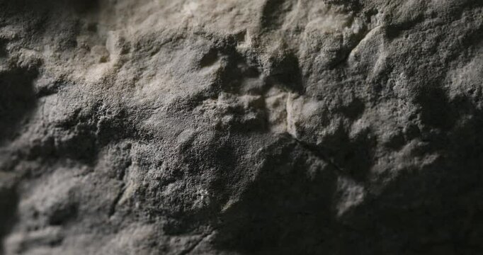 Close-up of dark textured sandstone with deep shadows and subtle relief