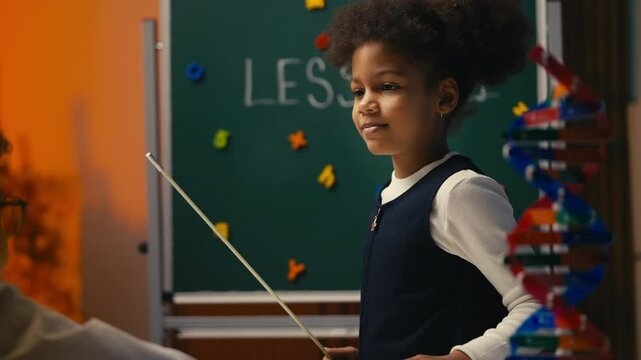 African American schoolgirl pretending to be strict teacher, holding pointer