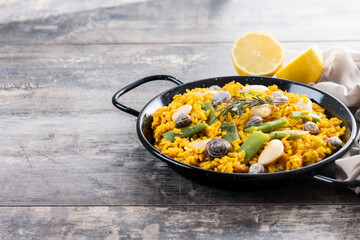 Traditional Valencian paella with rabbit, chicken, garrofon beans, snails, Moroccan green beans and saffron on wooden table