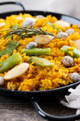 Traditional Valencian paella with rabbit, chicken, garrofon beans, snails, Moroccan green beans and saffron on wooden table. Close up