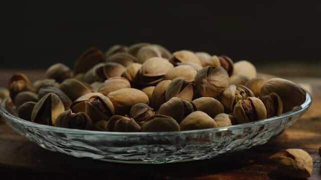 Roasted pistachios nuts in plate on dark background