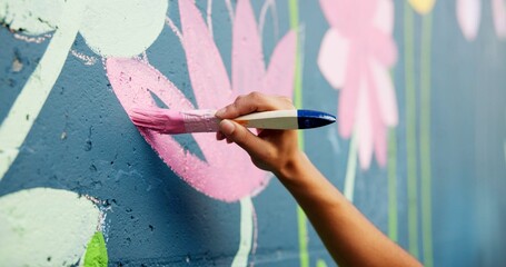 Person, hand or painting on wall art for mural, creativity or community service at building. Artist, paintbrush or outdoor with color for floral decor, creative process or flower for aesthetic design © peopleimages.com