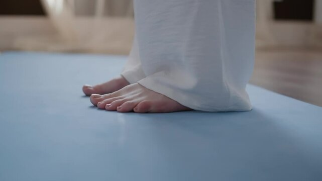 Close-up of a young woman's toes during meditation. The woman wiggles her toes and stands on her tiptoes.