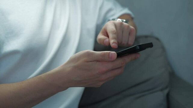 a smart guy with a tattoo on his hand uses a smartphone while sitting in a bright office with artificial light.
A person's hand typing a message on a telephone keyboard.
Smartphone, gadget, phone