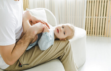 Best dad ever. A man tickles his daughter who is lying on his lap on the couch. father and child