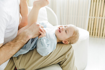 Best dad ever. A man tickles his daughter who is lying on his lap on the couch. father and child