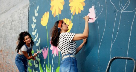 Women, teamwork or friends painting on wall for mural, drawing flowers or community service at...