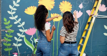 Women, teamwork or planning painting on wall for mural, drawing flowers or community service at building. Artist, back or girls with ladder for floral decoration, renovation or project for design © CineLens25/peopleimages.com