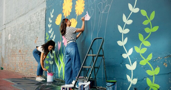 Girls, outdoor or friends painting on wall for mural, drawing flowers or community service at building. Artist, creative or women with teamwork for floral decoration, renovation or project for design