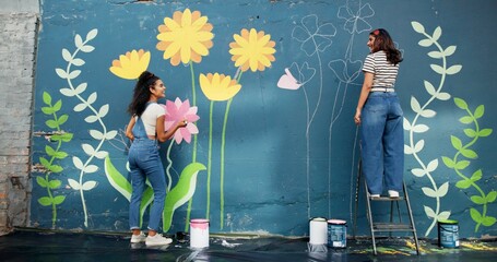 Women, talking or friends painting on wall for mural, drawing flowers or community service at building. Artist, creative or girls with teamwork for floral decoration, renovation or project for design © CineLens25/peopleimages.com