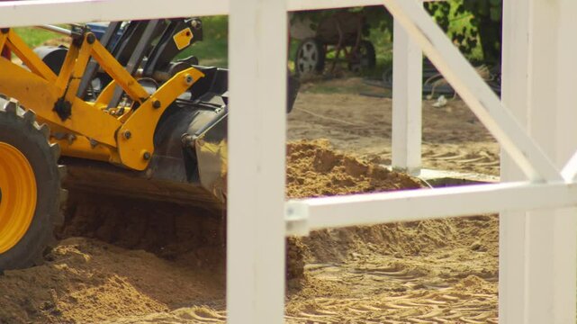 Yellow loader excavator leveling the ground at the construction site of the facility. Loading soil into the bucket, industry