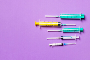 Top view of different syringes at purple background. Medical injection concept with copy space