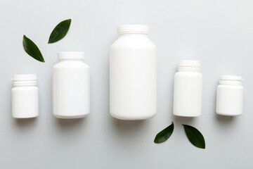supplement pills with medicine bottle health care and medical top view. Vitamin tablets. Top view mockup bottle for pills and vitamins with green leaves, natural organic bio supplement, copy space