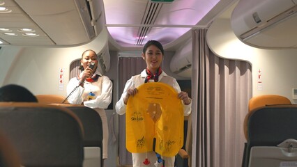 Asian stewardess safety explaining passengers prior to flight take off in airplane, air hostess...
