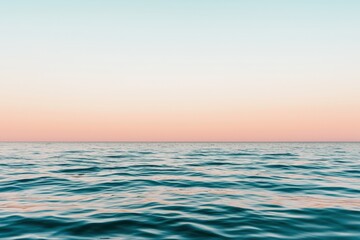 Obraz premium Pastel hues paint the sky above a tranquil ocean at dawn, reflecting serenity