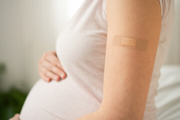 Focus on vaccination bandage on pregnant woman's arm. Responsible maternal healthcare through timely immunization during pregnancy.