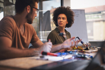 Young woman soldering a circuit boards in her tech office