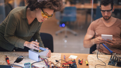 Young woman soldering a circuit boards in her tech office