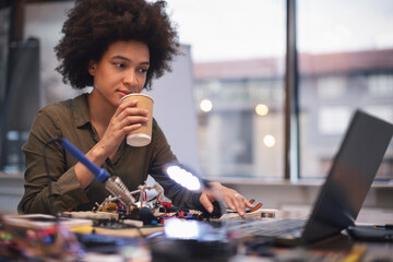 Young woman soldering a circuit boards in her tech office
