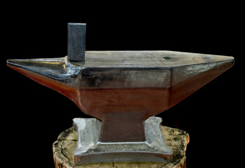 A new blacksmith anvil on a tree stump, isolated on black background
