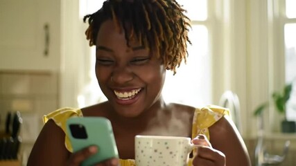 Woman, coffee and typing on smartphone in kitchen, reading social network notification and download funny multimedia. Happy african girl drinking tea, scroll on mobile app and laugh for meme at home