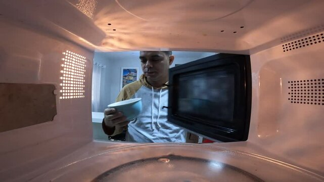 Man taking a bowl out of the microwave. Microwave concept. Bowl concept.