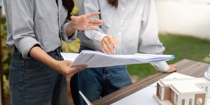 Innovative Sustainable Design. Architects analyzing building plans with a focus on eco-friendly solutions.