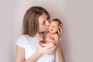 a mother with a newborn baby in her arms gently hugs and kisses him, a mother and a newborn baby in...