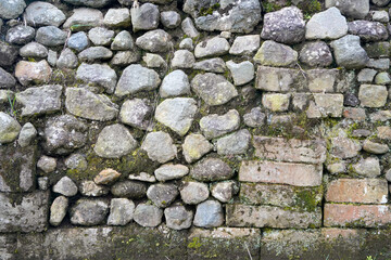 A Detailed Closeup of an Ancient Stone Wall with Moss and Brickwork: Rustic Texture and Architectural History