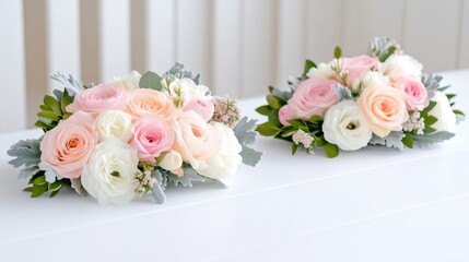 Two elegant floral arrangements with pink and white roses and greenery on a white surface, soft pastel colors, and wedding decor concept.