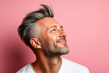 Fototapeta premium Conceptual art of style for aging men. Pink solid background. A warm and friendly man radiating happiness. Fashionable men's low fade haircut - midlife white man with grey hair.