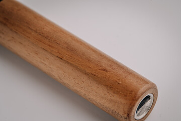 Macro close-up of the wooden handle of a vape device showing fine grain and metal grinder component, against a soft white background..