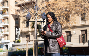 Young woman using smartphone in a city square during springtime