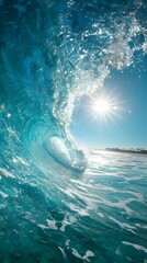 A stunning vertical shot captures the inside of a clear blue ocean wave as it s, with the bright sun shining over the distant beach, creating a beautiful scene.