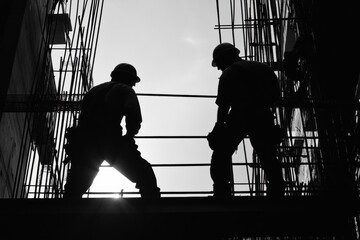 Silhouette of construction workers with hard hats building a structure. Ideal for illustrating industrial progress, teamwork, and infrastructure.