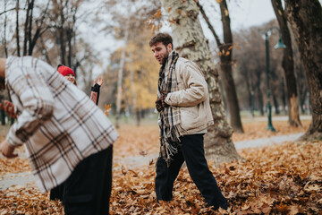 A joyful group of friends spending time together in a park during autumn, playing among fallen...