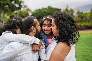 Happy indian family having fun playing with children outdoor at city park - Spring time, love and parenthood concept - Main focus on father's ear