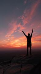 Fototapeta premium Silhouette of person with arms raised against a vibrant sunset sky, atop a rocky peak, representing achievement, freedom, and the beauty of nature