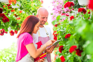 Garden center workers using digital tablet in greenhouse