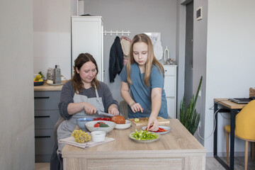 12 years old daughter and her mother cooking in domestic kitchen together, family lifestyle portrait