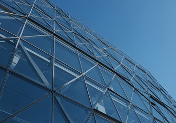 Fototapeta premium Modern Glass Facade of a Building Against a Blue Sky Architectural Design, Geometric Patterns, Reflection, Urban Landscape