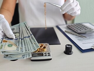 Jeweler evaluating cash and gold jewelry on a scale