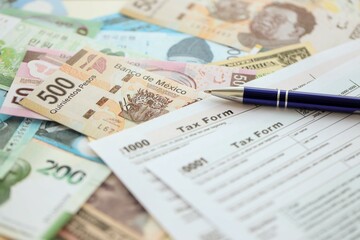 Big amount of money bills of different currencies and countries and tax report blank form ready to fill. Assortment background of international cash in big pile close up