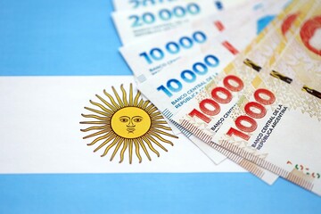 Argentine pesos money bills in big amount lies on Argentina flag close up