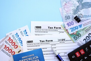 Argentine pesos money bills in big amount lies on table with pen, calculator, passport and tax forms