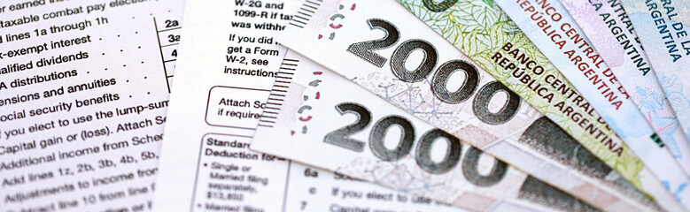 Argentine pesos money bills in big amount lies on table with pen and tax forms close up