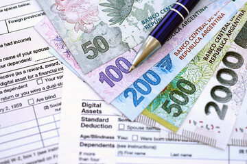 Argentine pesos money bills in big amount lies on table with pen and tax forms close up