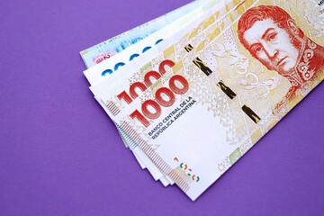 Argentine pesos money bills in big amount lies on purple color table close up