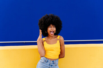 Beautiful young happy african woman with afro curly hairstyle strolling in the city - Cheerful black student girl walking on the street