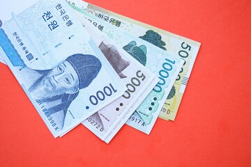 South Korean won money bills in big amount lies on red color table close up